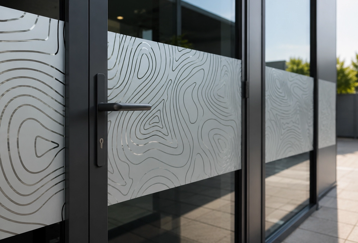 Texte alternatif : Détail d’un film opaque décoratif posé sur une porte vitrée professionnelle avec motif lignes topographiques.