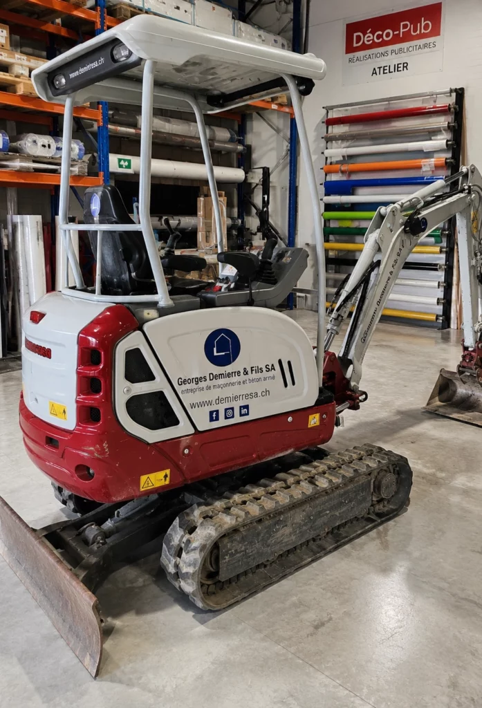 Machine de chantier compacte avec marquage adhésif professionnel dans un atelier de signalétique.
