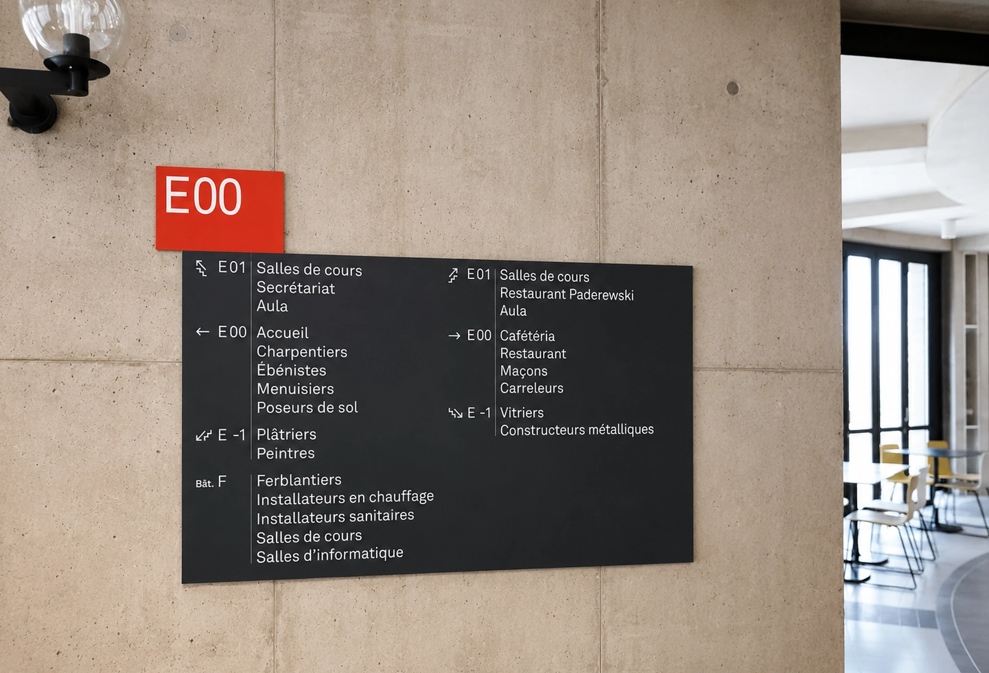 Panneau d'information mural fixé sur un mur en béton dans un bâtiment professionnel.