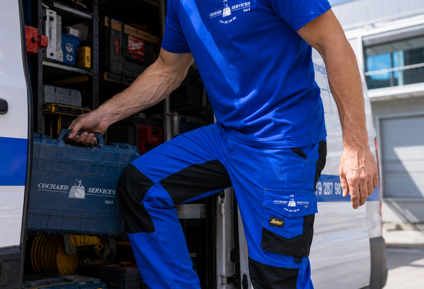 Détail d’un pantalon de travail personnalisé bleu avec poches renforcées et marquage textile blanc.