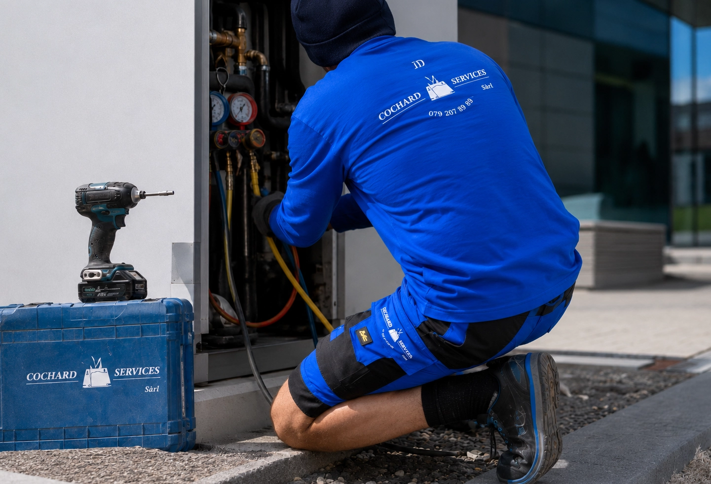 Technicien en short de travail personnalisé bleu intervenant sur une installation technique extérieure.