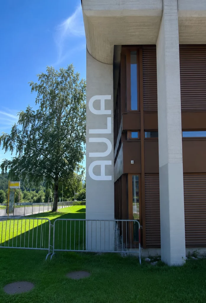 Grande lettre peinte sur une façade en béton pour identifier un bâtiment.