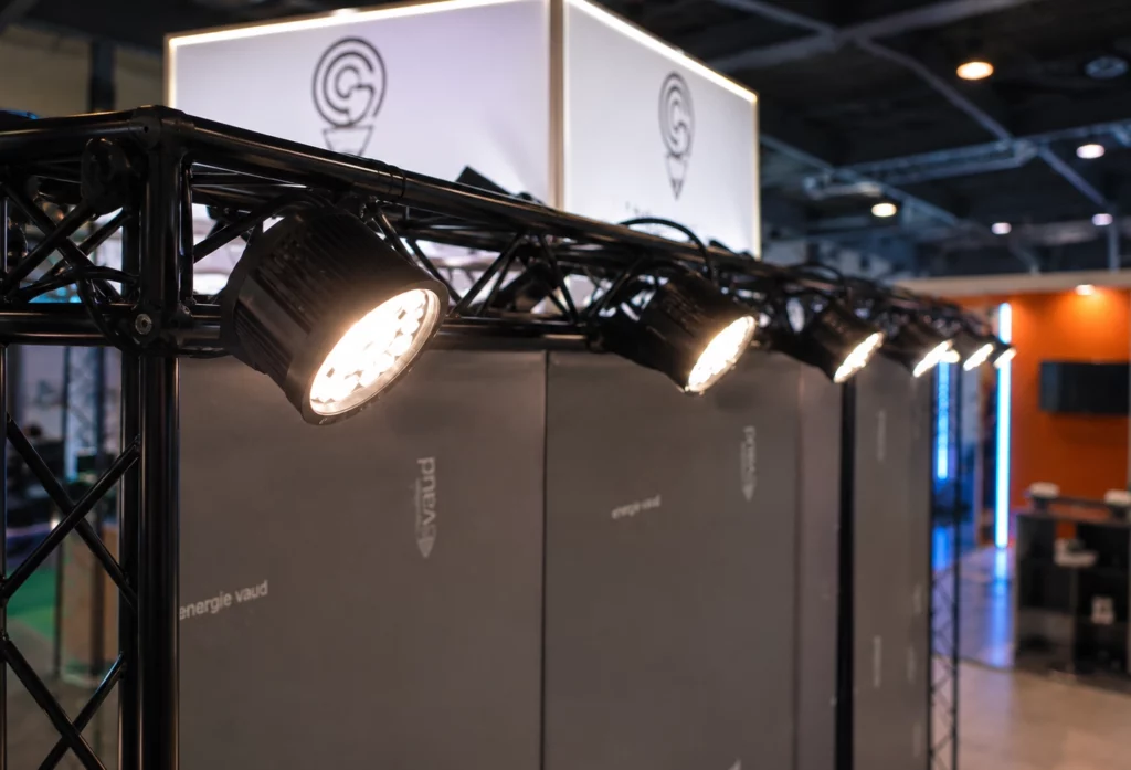 Détail d’un spot LED orientable installé sur une structure de stand pour éclairer un panneau d’exposition.