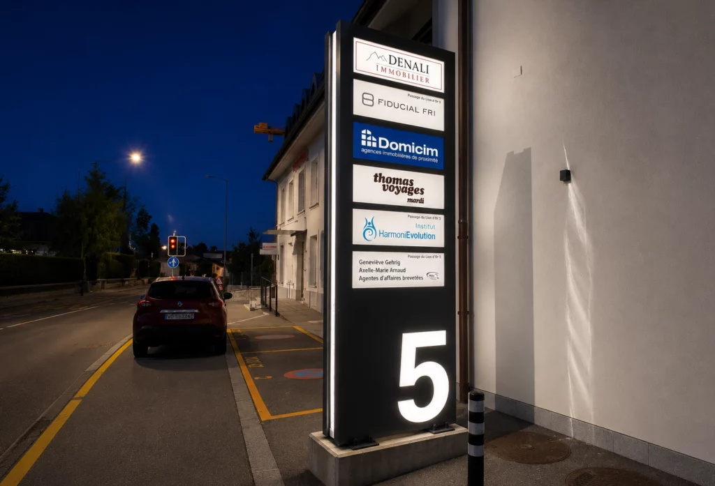 Totem lumineux visible de nuit devant une zone commerciale
